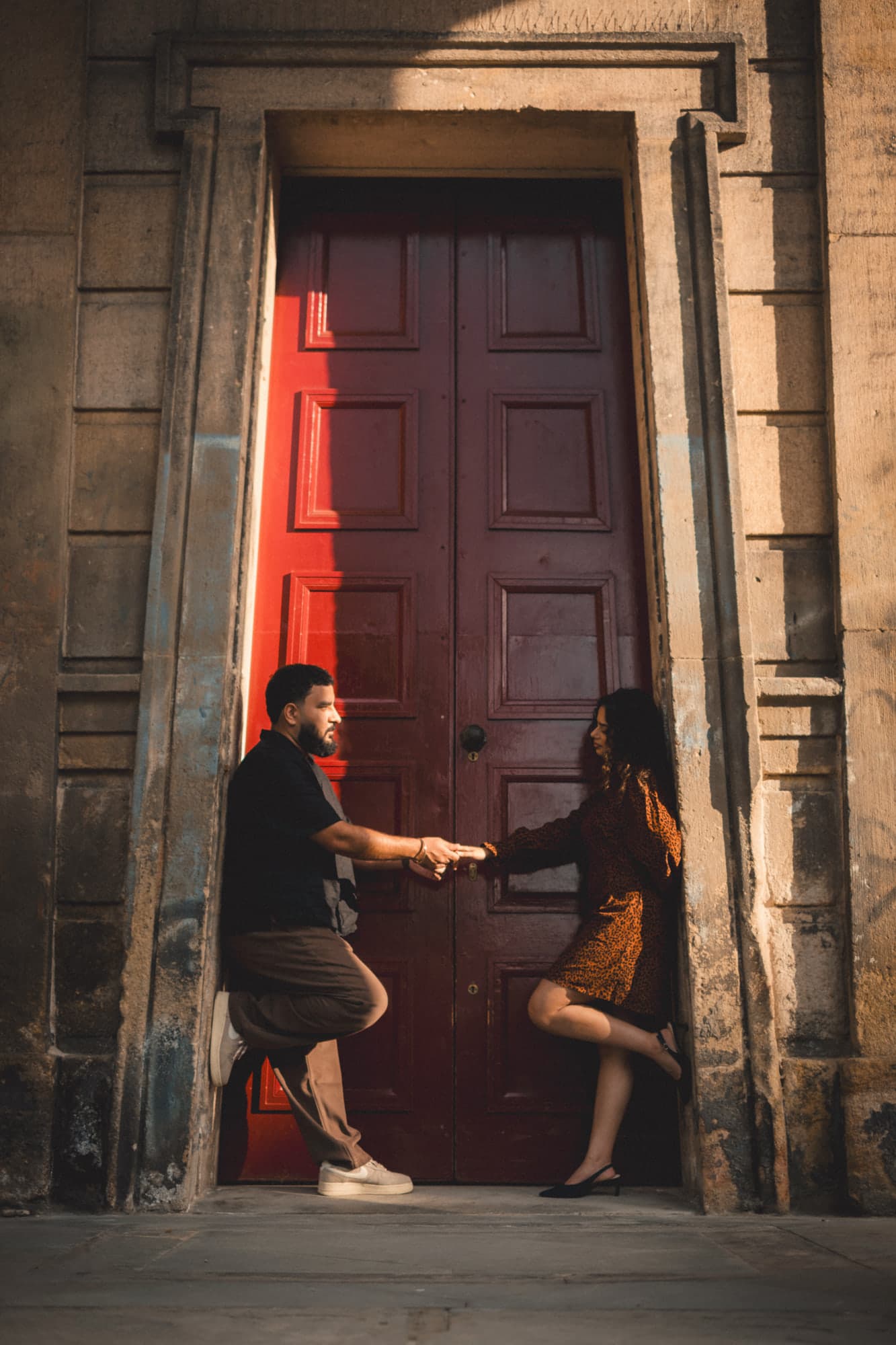 Talwinder and Ishmeet holding hands in a tall red doorway
