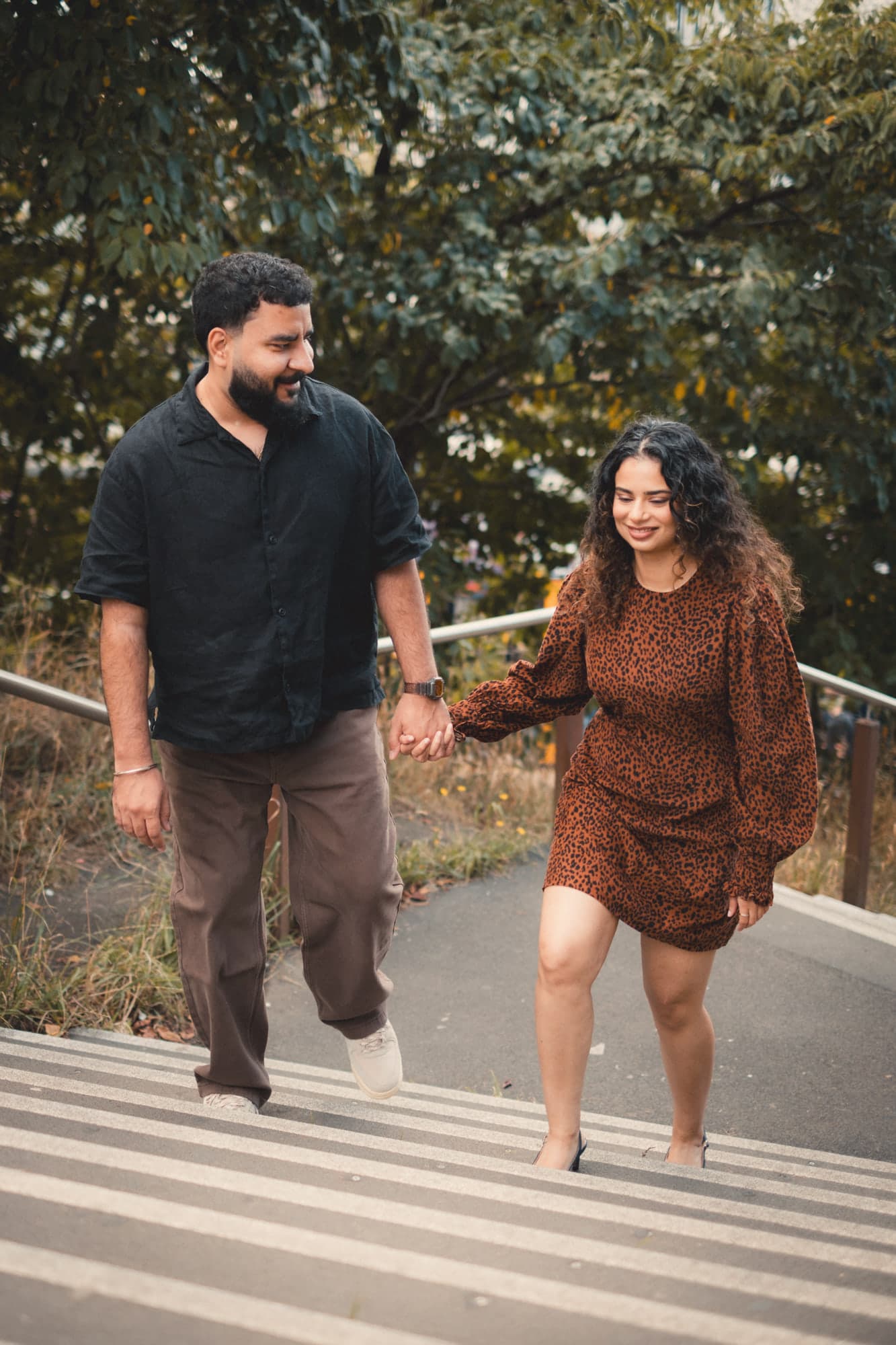 Talwinder and Ishmeet walking up a flight of steps hand in hand, he looking across at her as she smiles
