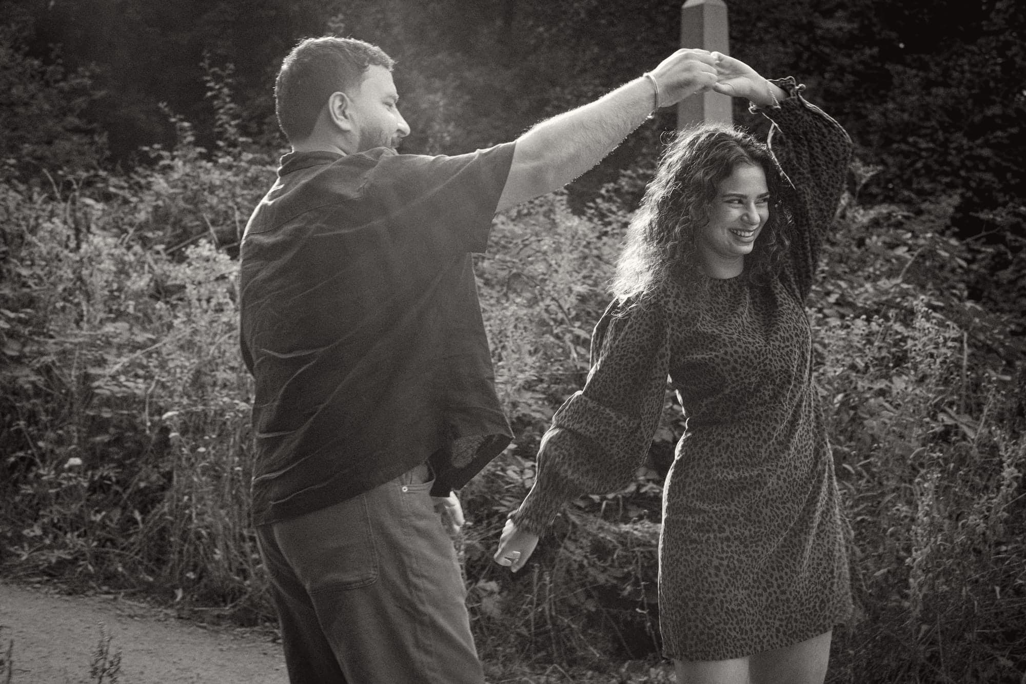 Talwinder turning Ishmeet under his arm in the low sun, in black and white